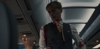 Movie still from “Blood Red Sky” (2021), directed by Peter Thorwarth – A man in a suit and tie with blood all over it; Medium shot, Over the shoulder angle