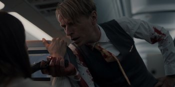 Movie still from “Blood Red Sky” (2021), directed by Peter Thorwarth – A man in a suit holding a knife with blood on it; Close Up shot, Over the shoulder angle