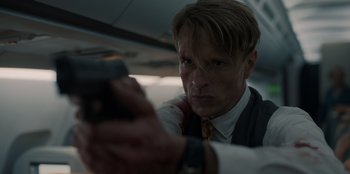 Movie still from “Blood Red Sky” (2021), directed by Peter Thorwarth – A man in a suit and tie holding a gun; Close Up shot, Low angle