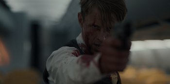Movie still from “Blood Red Sky” (2021), directed by Peter Thorwarth – A man with blood on his face is holding a gun; Close Up shot, Over the shoulder angle