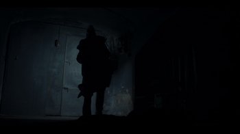 Movie still from “Blood Red Sky” (2021), directed by Peter Thorwarth – A person standing in a dark room holding a gun; Wide shot, High angle