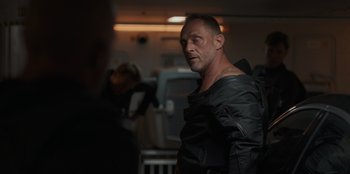 Movie still from “Blood Red Sky” (2021), directed by Peter Thorwarth – A man in a leather jacket standing in a room; Close Up shot, Over the shoulder angle