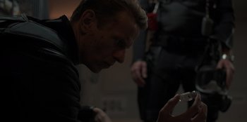 Movie still from “Blood Red Sky” (2021), directed by Peter Thorwarth – A man looking at his cell phone in a dark room; Close Up shot, High angle