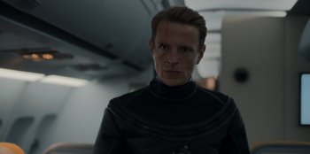 Movie still from “Blood Red Sky” (2021), directed by Peter Thorwarth – A man in a black wet - suit looking at the camera; Close Up shot, Low angle