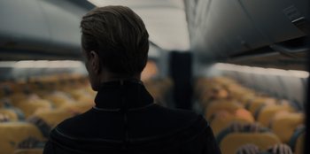 Movie still from “Blood Red Sky” (2021), directed by Peter Thorwarth – A person with short blonde hair wearing a black jacket; Close Up shot, Over the shoulder angle