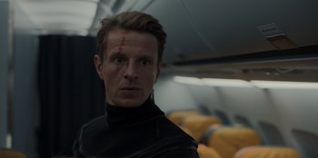 Movie still from “Blood Red Sky” (2021), directed by Peter Thorwarth – A person wearing a black shirt on a plane; Close Up shot, Low angle