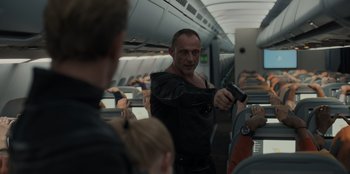 Movie still from “Blood Red Sky” (2021), directed by Peter Thorwarth – A man holding a gun on top of an airplane; Medium shot, Over the shoulder angle