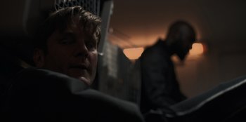 Movie still from “Blood Red Sky” (2021), directed by Peter Thorwarth – A man sitting in a car with a man standing behind him; Close Up shot, Over the shoulder angle