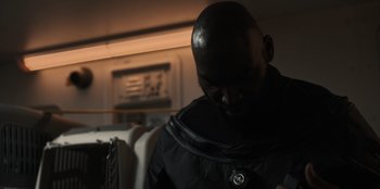 Movie still from “Blood Red Sky” (2021), directed by Peter Thorwarth – A man in a black outfit looking down at his cell phone; Close Up shot, Over the shoulder angle