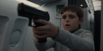 Movie still from “Blood Red Sky” (2021), directed by Peter Thorwarth – A young boy holding a gun in a room; Close Up shot, Low angle