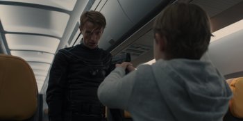 Movie still from “Blood Red Sky” (2021), directed by Peter Thorwarth – A man in black jacket holding a gun next to a child; Medium shot, Over the shoulder angle
