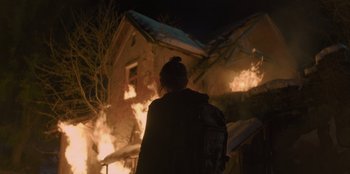Movie still from “Blood Red Sky” (2021), directed by Peter Thorwarth – A person standing in front of a house on fire at night; Wide shot, Over the shoulder angle
