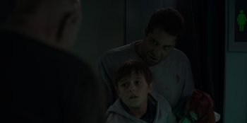 Movie still from “Blood Red Sky” (2021), directed by Peter Thorwarth – A man and a boy looking at each other in a dark room; Close Up shot, Over the shoulder angle