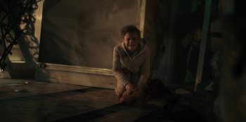Movie still from “Blood Red Sky” (2021), directed by Peter Thorwarth – A person sitting on the ground in front of a mirror; Close Up shot, Over the shoulder angle