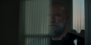 Movie still from “Blood Red Sky” (2021), directed by Peter Thorwarth – A man with a gray beard looking out a window; Close Up shot, Low angle
