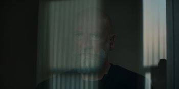 Movie still from “Blood Red Sky” (2021), directed by Peter Thorwarth – A man with a gray beard looking out of a window; Close Up shot, Low angle