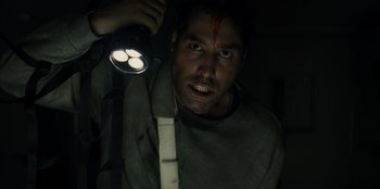 Movie still from “Blood Red Sky” (2021), directed by Peter Thorwarth – A man holding a flashlight in a dark room; Close Up shot, Low angle
