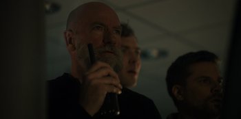 Movie still from “Blood Red Sky” (2021), directed by Peter Thorwarth – A man with a bald head and a goatee is holding a cell phone; Close Up shot, Low angle