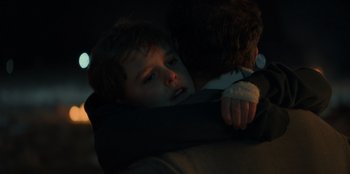 Movie still from “Blood Red Sky” (2021), directed by Peter Thorwarth – A young boy holding onto the arm of a man; Close Up shot, Over the shoulder angle