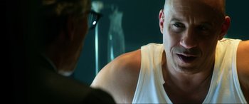 Movie still from “Bloodshot” (2020), directed by Dave Wilson – A bald man wearing a white tank top and glasses; Close Up shot, Over the shoulder angle
