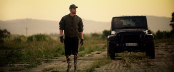 Movie still from “Bloodshot” (2020), directed by Dave Wilson – A man with a prosthetic leg standing in front of a jeep; Wide shot, Low angle