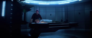 Movie still from “Bloodshot” (2020), directed by Dave Wilson – A man standing next to a man laying on a bed; Wide shot, High angle