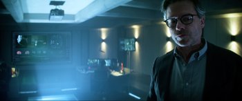 Movie still from “Bloodshot” (2020), directed by Dave Wilson – A man standing in front of a tv in a dark room; Medium shot, Over the shoulder angle