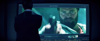 Movie still from “Bloodshot” (2020), directed by Dave Wilson – A man in a suit looking at an image of a man with a gun; Close Up shot, Over the shoulder angle
