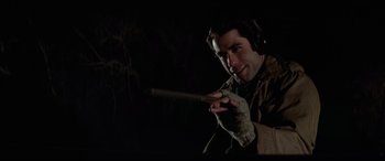 Movie still from “Blow Out” (1981), directed by Brian De Palma – A man wearing ear muffs holding a wooden stick; Close Up shot, Over the shoulder angle