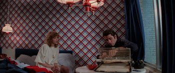 Movie still from “Blow Out” (1981), directed by Brian De Palma – A man and a woman sitting at a table in a room; Medium shot, High angle