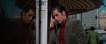 Movie still from “Blow Out” (1981), directed by Brian De Palma – A man talking on a phone while standing next to a building; Close Up shot, Low angle