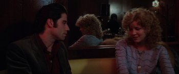 Movie still from “Blow Out” (1981), directed by Brian De Palma – A man and a woman sitting at a table in front of each other; Medium shot, Over the shoulder angle