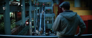 Movie still from “Blow Out” (1981), directed by Brian De Palma – A man standing in front of an escalator; Wide shot, High angle