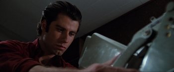 Movie still from “Blow Out” (1981), directed by Brian De Palma – A man looking at a laptop computer in a dark room; Close Up shot, Low angle