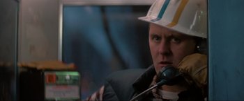 Movie still from “Blow Out” (1981), directed by Brian De Palma – A man in a hard hat is talking on the phone; Close Up shot, Low angle