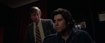 Movie still from “Blow Out” (1981), directed by Brian De Palma – A man in a suit and tie next to another man in a suit and tie; Close Up shot, Over the shoulder angle