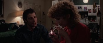 Movie still from “Blow Out” (1981), directed by Brian De Palma – A man and a woman are looking at a flashlight; Medium shot, Over the shoulder angle