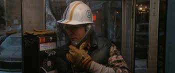 Movie still from “Blow Out” (1981), directed by Brian De Palma – A man wearing a hard hat talking on a cell phone; Close Up shot, Low angle