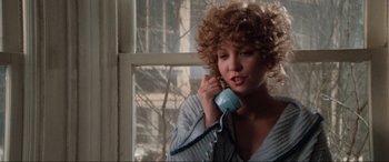 Movie still from “Blow Out” (1981), directed by Brian De Palma – A young woman talking on a phone while standing in front of a window; Close Up shot, High angle