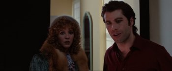 Movie still from “Blow Out” (1981), directed by Brian De Palma – A man and a woman standing next to each other in front of a mirror; Medium shot, Over the shoulder angle