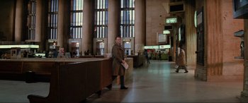 Movie still from “Blow Out” (1981), directed by Brian De Palma – A man in a trench coat standing in a train station; Extreme Wide shot, Over the shoulder angle