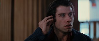 Movie still from “Blow Out” (1981), directed by Brian De Palma – A person holding a cell phone up to their ear; Close Up shot, Over the shoulder angle