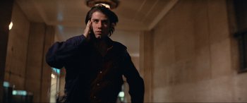 Movie still from “Blow Out” (1981), directed by Brian De Palma – A man in a dark room holding a cell phone to his ear; Medium shot, Low angle