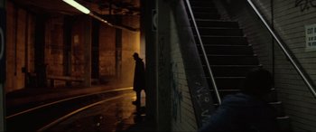 Movie still from “Blow Out” (1981), directed by Brian De Palma – A man walking down a street next to a staircase; Wide shot, Over the shoulder angle