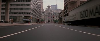 Movie still from “Blow Out” (1981), directed by Brian De Palma – An empty city street in front of tall buildings; Extreme Wide shot, High angle