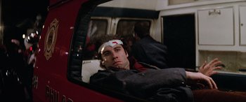 Movie still from “Blow Out” (1981), directed by Brian De Palma – A man with a bandage on his head sitting in the back of a car; Close Up shot, Low angle