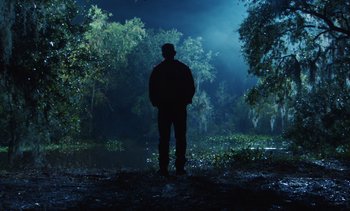 A man standing in the woods at night