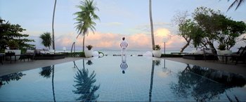 Movie still from “Blue Beetle” (2023), directed by Angel Manuel Soto – A man standing in a pool looking out at the ocean; Extreme Wide shot, Low angle