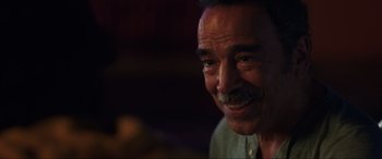 Movie still from “Blue Beetle” (2023), directed by Angel Manuel Soto – An older man with a mustache is smiling for the camera; Close Up shot, Over the shoulder angle