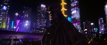 Movie still from “Blue Beetle” (2023), directed by Angel Manuel Soto – A statue of a man wearing a mask in a city at night; Extreme Wide shot, Low angle